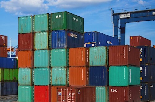 verschiedenfarbige Container stehen aufgestapelt an einem Hafen